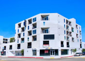 Thumbnail 3 of 75 - a white apartment building with balconies and a red and white sign on the side of the