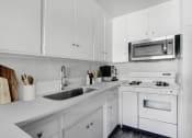 Thumbnail 13 of 52 - a kitchen with white cabinets and a sink and a microwave