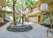 Thumbnail 49 of 49 - A courtyard with a statue surrounded by a gravel circle and a bench.