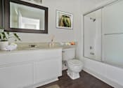 Thumbnail 15 of 35 - A white toilet sits in a bathroom next to a sink and a shower.