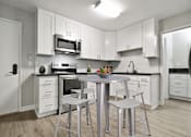 Thumbnail 34 of 76 - Open kitchen with stainless steel electric stove with micro hood microwave, tile backsplash, white kitchen cabinets, gray quartz counter tops, bathroom on the right