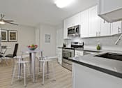 Thumbnail 32 of 76 - Open kitchen with stainless steel electric stove with micro hood microwave, tile backsplash, white kitchen cabinets, gray quartz counters