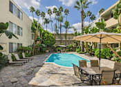 Thumbnail 7 of 28 - A pool surrounded by chairs and trees.