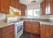 Thumbnail 7 of 48 - Kitchen with white gas stove, granite countertops, wood style kitchen cabinets
