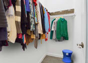 Thumbnail 9 of 32 - a closet with a rack of clothes and a blue stool