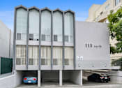 Thumbnail 25 of 31 - the building has a parking lot with cars in front of it