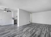 Thumbnail 62 of 66 - an empty living room with a ceiling fan and a kitchen in the background