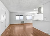 Thumbnail 28 of 31 - an empty living room and kitchen with wood floors and white walls