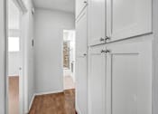 Thumbnail 27 of 31 - an empty room with white cabinets and a hallway with a door to a kitchen