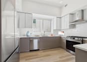 Thumbnail 19 of 163 - A modern kitchen with a stainless steel refrigerator and wooden flooring.