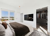 Thumbnail 26 of 163 - A bedroom with a large bed and a wardrobe with clothes hanging in it.