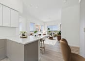 Thumbnail 1 of 163 - A kitchen with white cabinets and a large island with a plant on it.