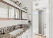 Thumbnail 49 of 81 - A bathroom with a marble counter top and a shower with a curtain.