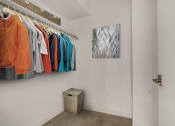 Thumbnail 26 of 38 - a walk in closet in a bedroom with a door and a painting on the wall