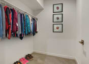 Thumbnail 32 of 38 - a walk in closet with clothes hanging on a rack and shoes on the floor