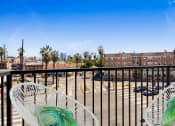 Thumbnail 17 of 38 - a balcony with two white chairs and a view of a parking lot