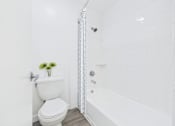Thumbnail 7 of 76 - A white toilet with a white bathtub and a white shower curtain.
