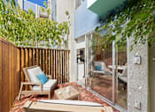 Thumbnail 4 of 76 - A wooden chair with a blue pillow sits on a patio.