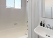 Thumbnail 5 of 5 - A white bathroom with a tub, sink, and window.