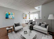 Thumbnail 3 of 5 - A modern living room with a white couch and a painting on the wall.