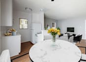 Thumbnail 1 of 5 - A white marble table with a vase of yellow flowers is in the middle of a modern kitchen and dining room.