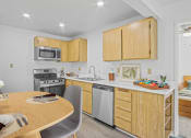 Thumbnail 3 of 52 - a kitchen and dining area with wooden cabinets and stainless steel appliances