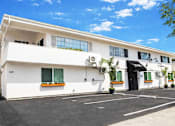 Thumbnail 2 of 14 - A white building with a black door and windows.