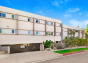 Thumbnail 65 of 66 - a white apartment building with a sidewalk and grass in front of it