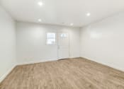 Thumbnail 45 of 66 - a living room with white walls and wood flooring and a white door