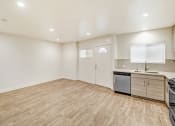 Thumbnail 37 of 66 - the living room and kitchen of an apartment with a wooden floor and white walls