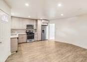 Thumbnail 35 of 66 - an empty living room with a kitchen with stainless steel appliances