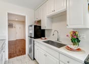 Thumbnail 43 of 79 - A kitchen with white cabinets and a black refrigerator.
