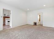 Thumbnail 7 of 13 - an empty living room with white walls and a white kitchen