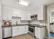 Thumbnail 9 of 76 - Kitchen with stainless steel dishwasher, electric stove, microwave, gray quartz countertops, tile backsplash