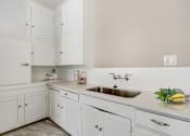 Thumbnail 6 of 8 - a white kitchen with a sink and white cabinets