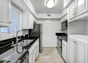 Thumbnail 2 of 18 - a kitchen with white cabinets and black counter tops and a sink