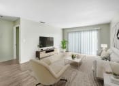 Thumbnail 2 of 15 - a living room with a couch and a chair and a television