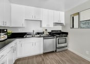 Thumbnail 1 of 15 - an empty kitchen with white cabinets and stainless steel appliances