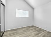 Thumbnail 58 of 62 - a bedroom with white walls and wood flooring and a window