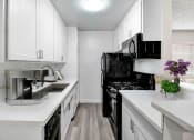 Thumbnail 6 of 95 - a renovated kitchen with white cabinets and black appliances