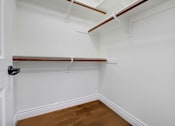 Thumbnail 47 of 88 - a walk in closet with white walls and a wood floor