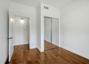 Thumbnail 44 of 88 - a bedroom with white walls and wood floors and a mirrored closet