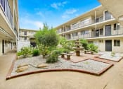 Thumbnail 11 of 14 - a courtyard with a fountain and benches in front of an apartment building