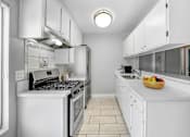 Thumbnail 38 of 65 - a white kitchen with a bowl of fruit on the counter