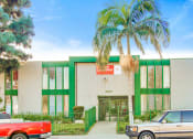 Thumbnail 15 of 17 - a green and white building with a palm tree in front of it