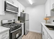 Thumbnail 2 of 91 - a white kitchen with stainless steel appliances and white cabinets