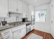 Thumbnail 1 of 57 - a kitchen with white cabinets and black counter tops and a window