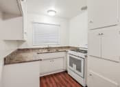 Thumbnail 1 of 48 - Kitchen with granite countertops, white gas range, white cabinets, and wood style flooring