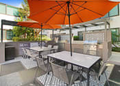Thumbnail 62 of 64 - a patio with tables and chairs and an orange umbrella