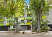 Thumbnail 61 of 61 - a building with green balconies and trees in front of it
